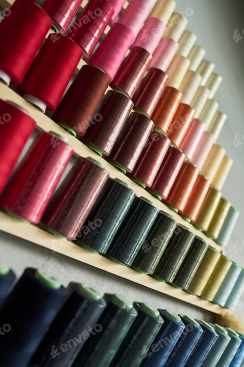 Preview: Colorful Spools of Sewing Thread Arranged in Rows on Wooden Shelves
