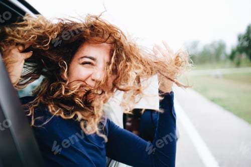 Preview: Happy woman with windy funny hair on a road trip