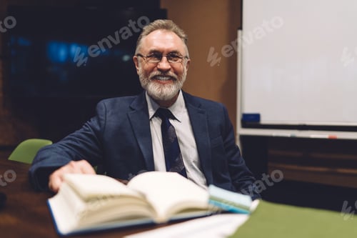 Preview: Happy male entrepreneur with notepad in modern workspace
