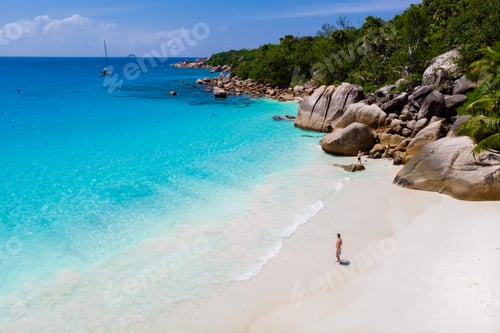 Preview: young man on a white beach with turquoise colored ocean, Anse Lazio beach Praslin Island Seychelles