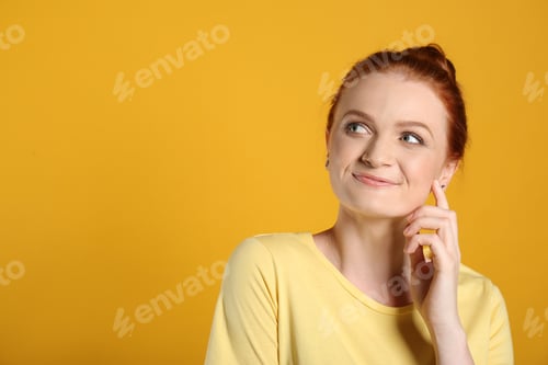 Preview: Portrait of happy red haired woman on yellow background, space for text
