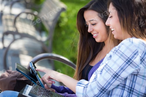 Preview: Two Happy Mixed Race Students Using Touch Pad Computer Outside Together on Campus.