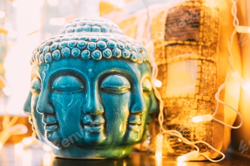 Preview: Blue statue of Buddha head lighted by bokeh boke lights. Interior element