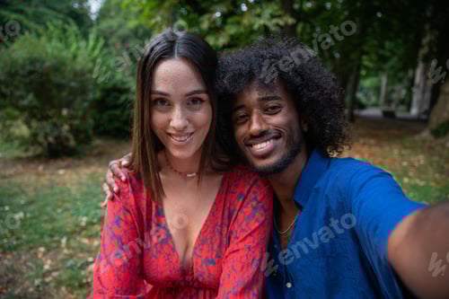 Preview: Selfie of two people, a male and a female sitting on a bench in a park. Smiling couple or friends.