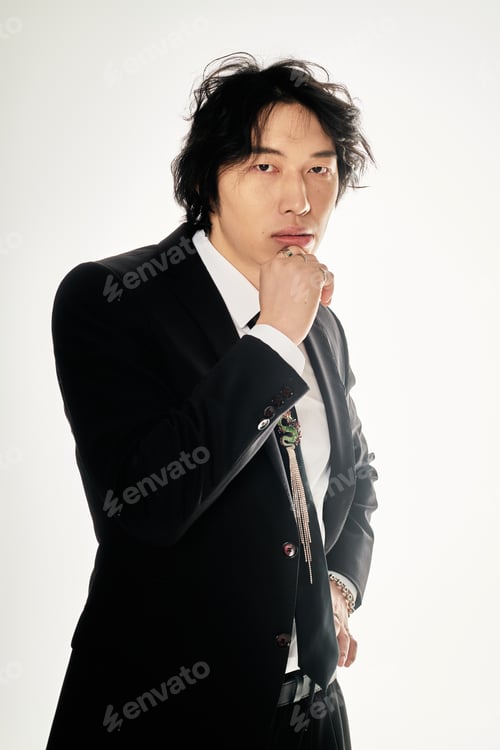 Preview: Stylish young asian man confidently posing in modern attire against a plain backdrop