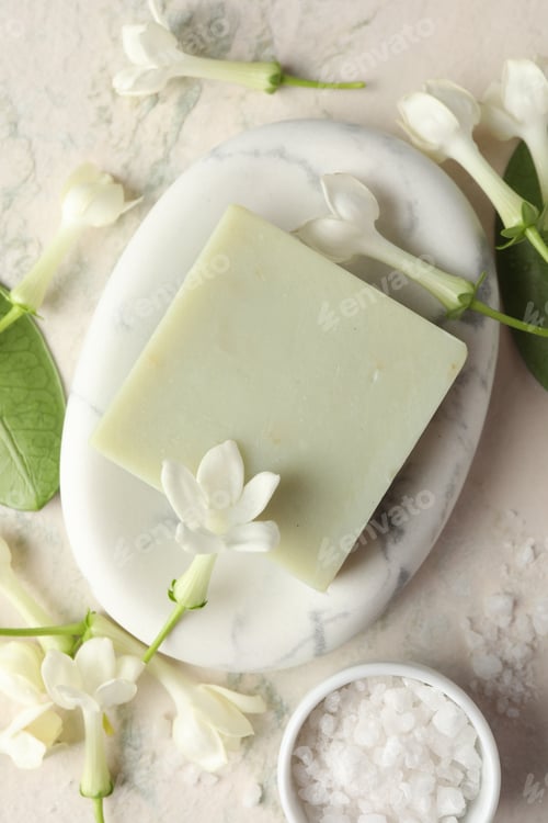 Visualização: Barra de sabão, sal marinho e flores de jasmim em mesa de luz, camada plana