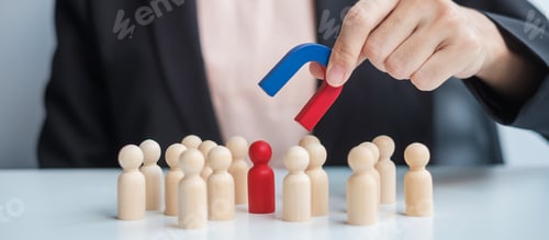 Preview: Business woman hand holding magnet and pulling man wooden figure from the crowd employee. Business