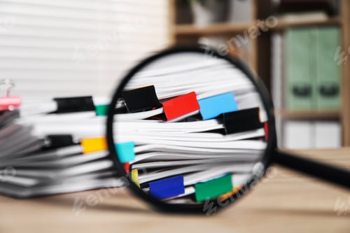 Preview: Stack of documents with binder clips and magnifying glass on wooden table indoors, closeup