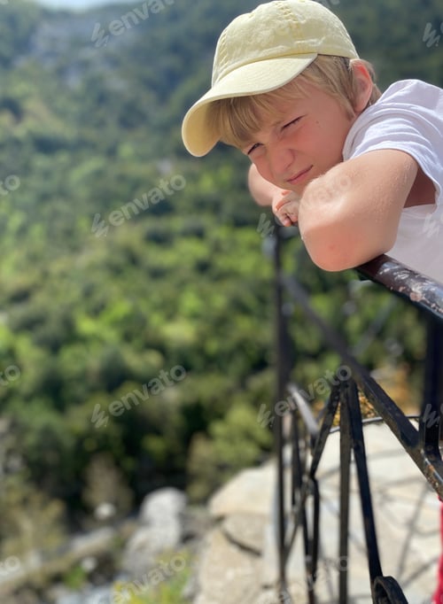 Preview: Boy 9 years old standing on the terrace, with view to the mountains and forest