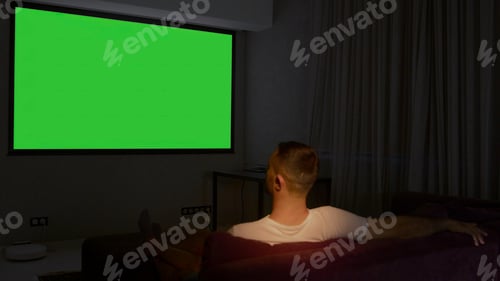Preview: Viewing on a projector in a closed room. Media. A man looking into a green screen that is shown on a