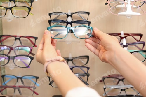 Preview: Female ophthalmologist taking glasses from showcase in optical store