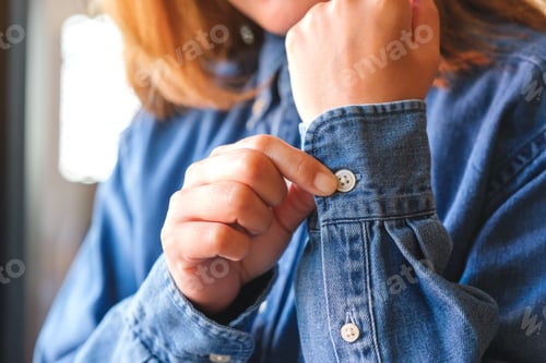 Preview: Closeup of a woman buttoning her jeans shirt sleeve
