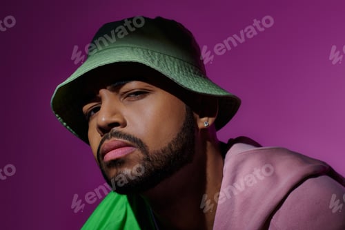 Vista previa: handsome young man in green panama with earring looking suspiciously at camera, fashion concept