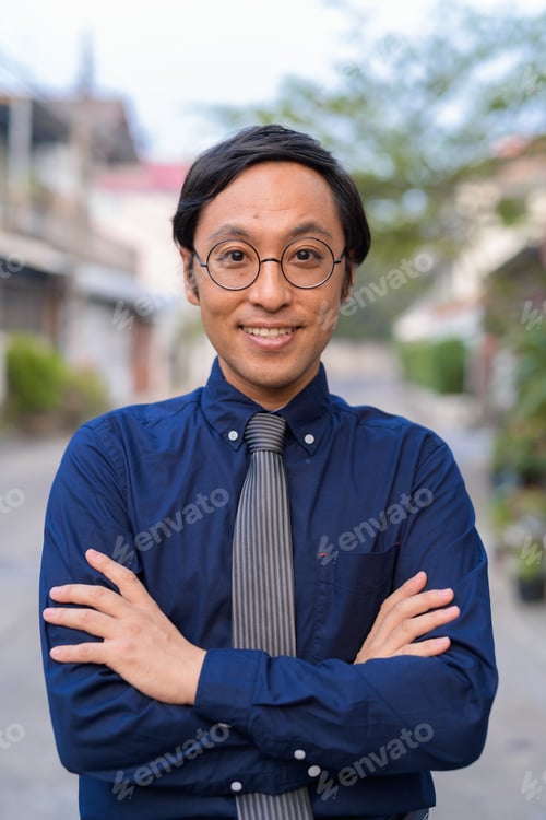 Preview: Face of Japanese businessman with arms crossed outdoors