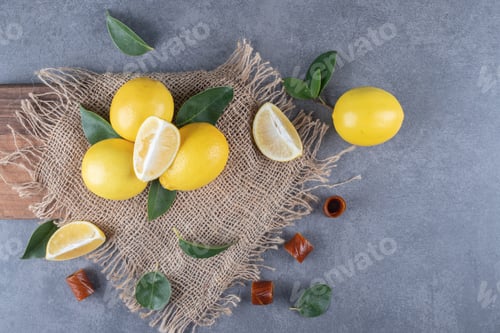 Preview: Top view. Fresh lemons and slices on sack over wooden board