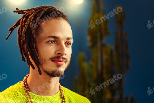 Preview: Portrait of a positive handsome caucasian guy with dreadlocks against blue background