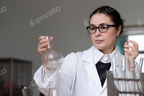 Preview: Woman Scientist Examining Glassware in Laboratory Setting