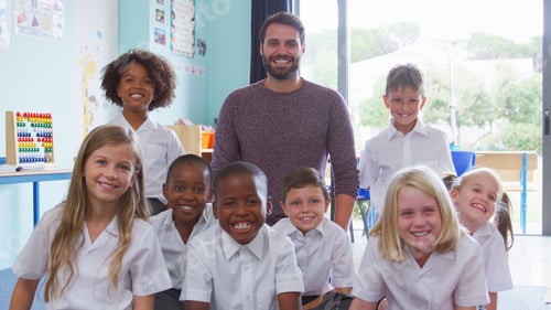Preview: Portrait Of Elementary School Pupils Wearing Uniform Sitting On Floor In Classroom With Male Teacher