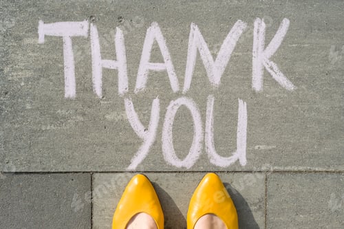Preview: Female feet with text thank you written on grey sidewalk