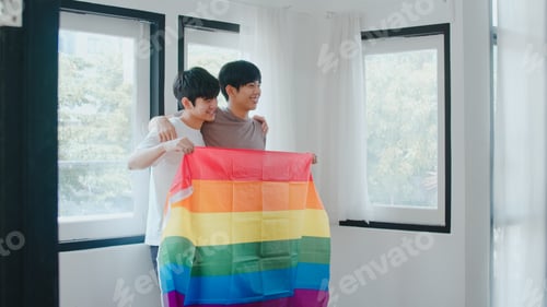 Preview: Portrait Young Asian Gay couple feeling happy showing rainbow flag at home.