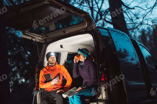 Preview: A couple enjoying a cozy evening by their van in the woods, illuminated by soft light. Camping in na