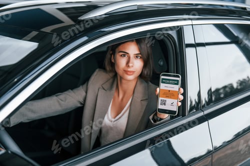 Preview: Woman testing new car. Sitting indoors in modern automobile