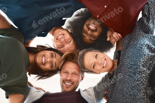 Preview: Low-angle portrait of a team of happy designers posing with their heads in a huddle in the office