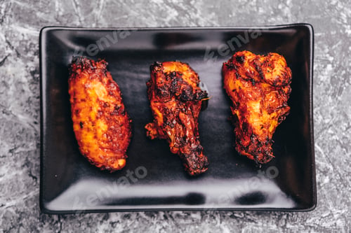 Preview: Fried chicken portions on a black plate.