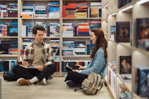 Preview: Two students engaged in conversation in library aisle