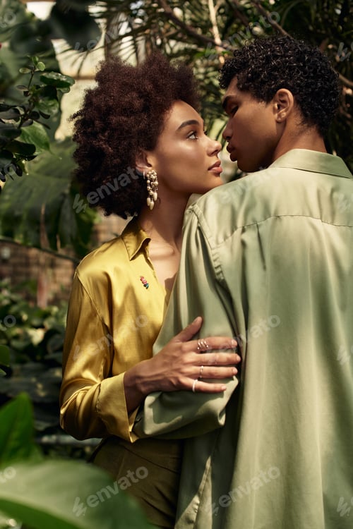 Preview: Young couple shares tender moment in lush greenhouse filled with vibrant greenery and plants