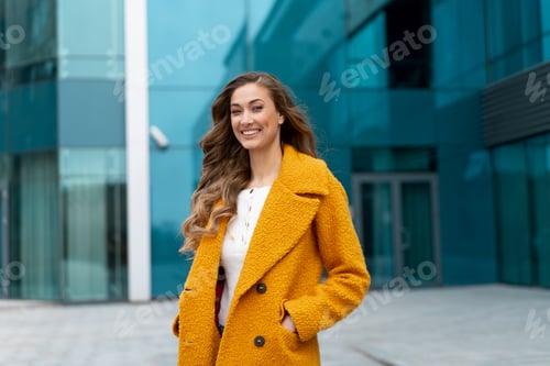 Preview: Business woman standing near corporative building outdoor dressed yellow stylish coat