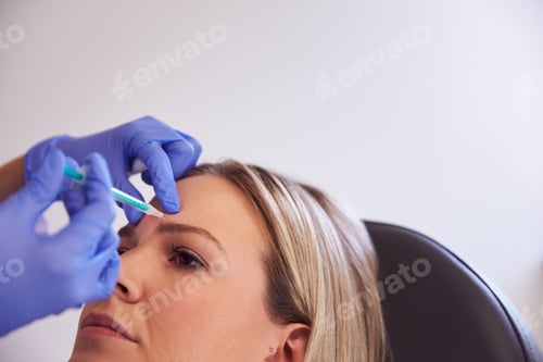 Preview: Woman Sitting In Chair Being Give Botox Injection In Forehead By Female Doctor