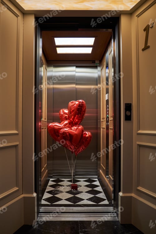 Preview: Doorway of hotel room leading to lift with red balloons