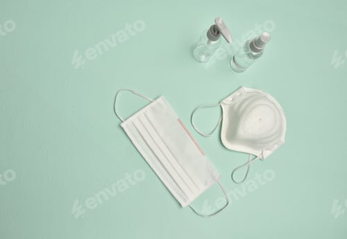 Preview: Top view of medical masks and bottles of disinfectant on a blue table