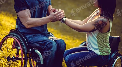 Preview: A man in wheelchair holds the arms of handicapped female.