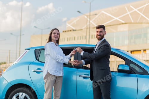 Visualização: O vendedor de carros do sexo masculino entrega as chaves para a compradora, o contrato de compra é