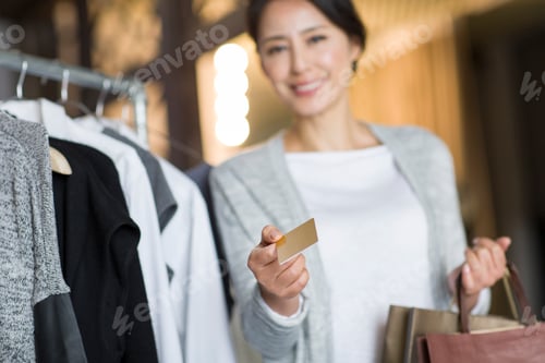 Preview: Mature woman with credit card in clothing store