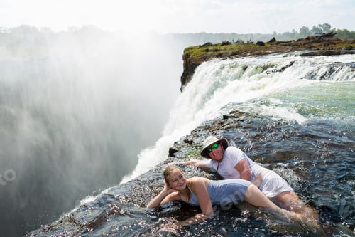 Preview: Man and a girl in the water of the Devil's Pool on the edge of Victoria Falls.