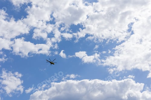 Preview: Blue sky with airy white clouds and a flying helicopter.