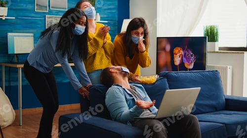 Preview: Multi ethnic friends wearing face mask eating snacks using laptop