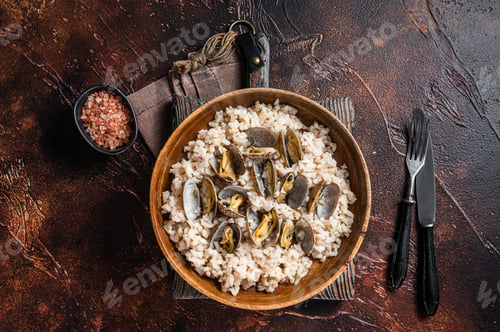Preview: Risotto with clams and seafood in a wooden plate. Dark backgroud. Top view