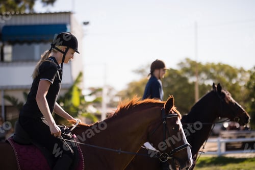 Preview: Side view of friends riding horses at barn