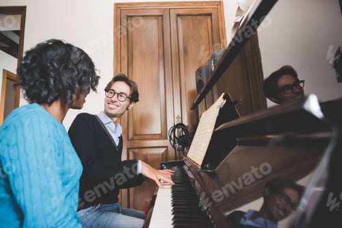 Preview: Young handsome mixed race couple in their house both playing piano