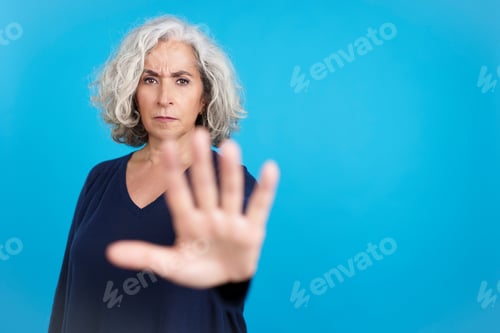 Preview: Serious mature woman gesturing with her hand prohibition
