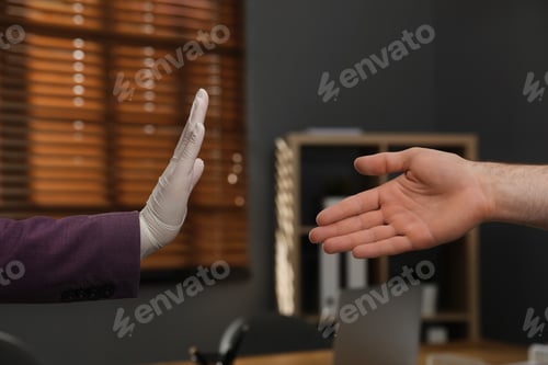 Preview: Woman refusing handshake from coworker in office, closeup