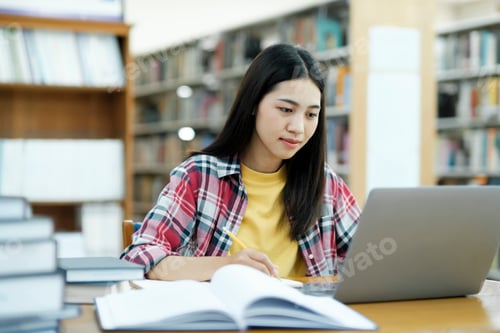 Preview: Young university student using laptop for online learning, searching and learning at library.