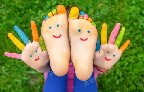 Preview: Feet of a child on the grass with a painted smile. Selection focus.