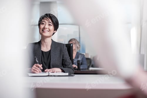 Preview: Smiling woman sitting at desk in city office