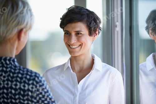 Aperçu: Portrait of smiling smiling businesswoman looking at colleague at the window in office