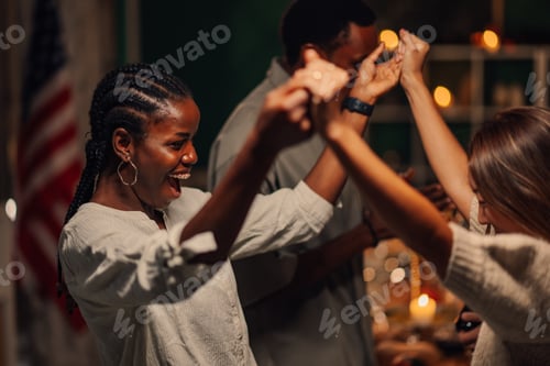 Preview: Friends holding hands and dancing together at home party